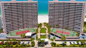 Un hotel moderno de gran altura con varias plantas, una cancha de tenis y vistas a la playa.