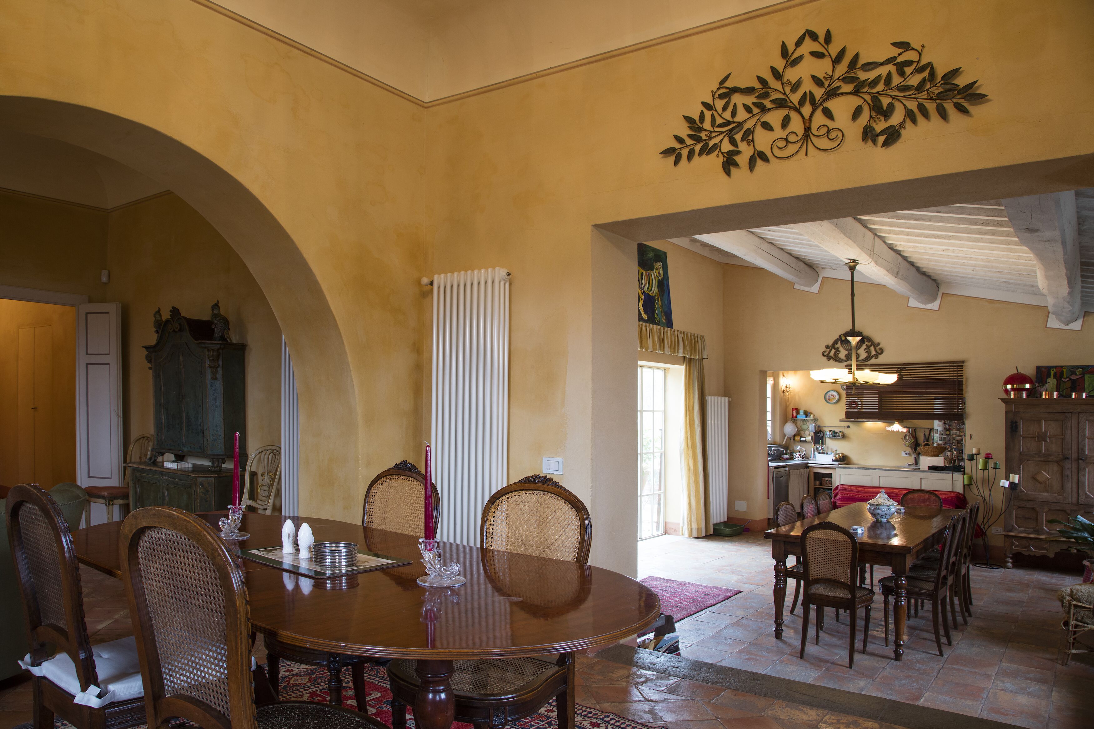 A dining area with a large wooden table and chairs, a radiator, and a decorative wall piece.