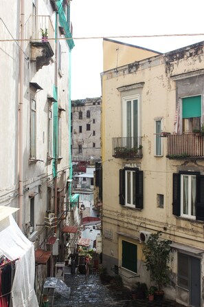 A narrow alleyway between buildings with balconies, potted plants, and outdoor seating. - B&B Le Chiavi Di Casa (Naples)