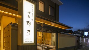 A building with a large illuminated sign in Japanese characters, a covered entrance, and a staircase leading up to the entrance.