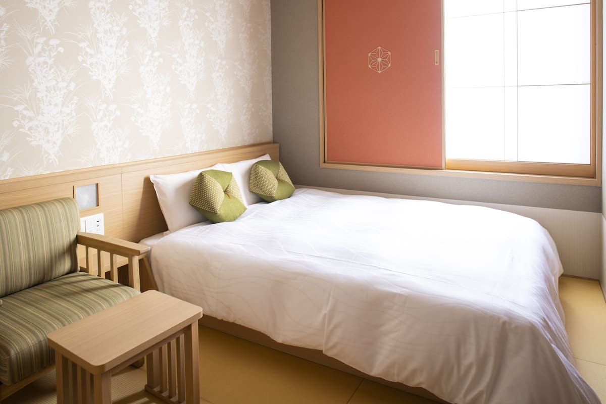 Une chambre à coucher bien rangée, avec un lit, une petite table en bois et une chaise.