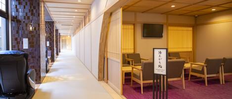 A hotel corridor with a reception desk, seating area, and a relaxation room sign.