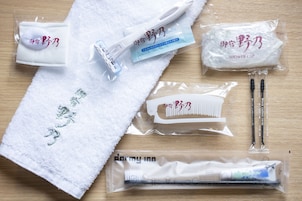 A towel, a shower cap, a comb, and a toothbrush set on a wooden surface.