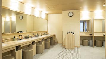 A modern bathroom with wooden fixtures, a large mirror, a clock, and a towel rack.