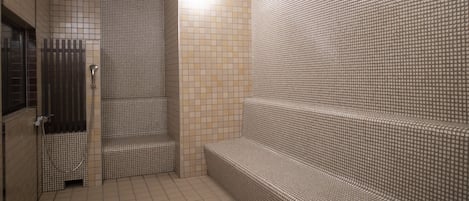 Un baño con piso de baldosas, un banco y zona de ducha.