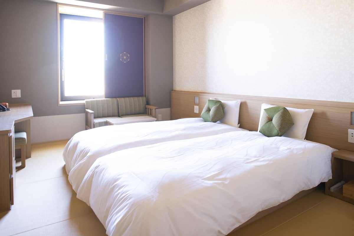 Une chambre d’hôtel avec deux lits, un bureau et une fenêtre.