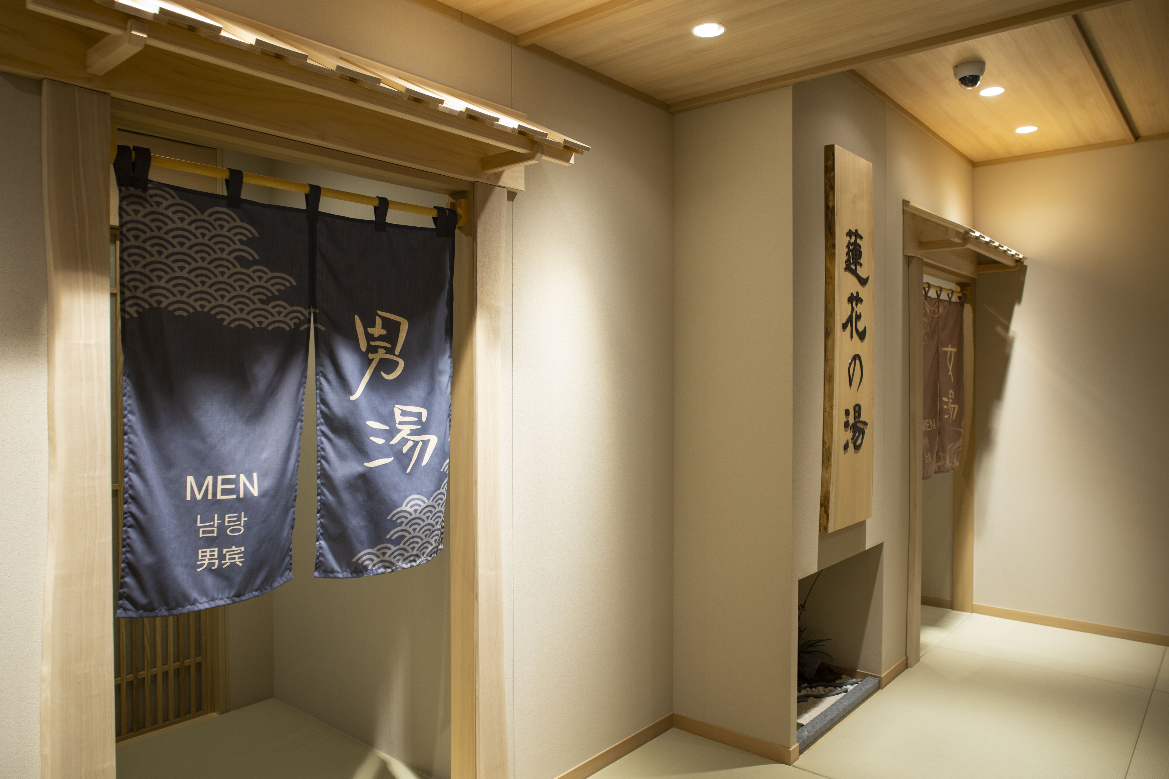 A traditional Japanese interior with tatami flooring, shoji screens, and hanging banners with Japanese characters.