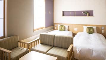 A hotel room with a bed, two sofas, a small table, and a window.