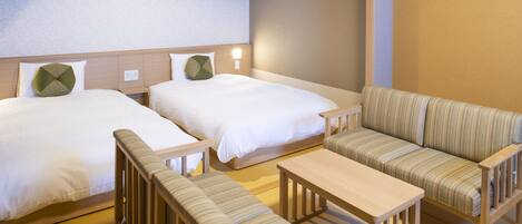 A hotel room with two single beds, a sofa, and a small table.