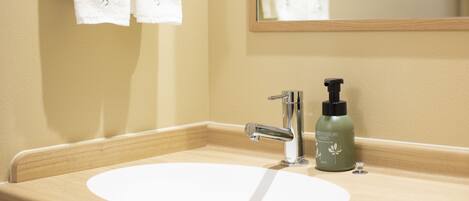 A bathroom sink with a mirror, a faucet, and a bottle of soap.