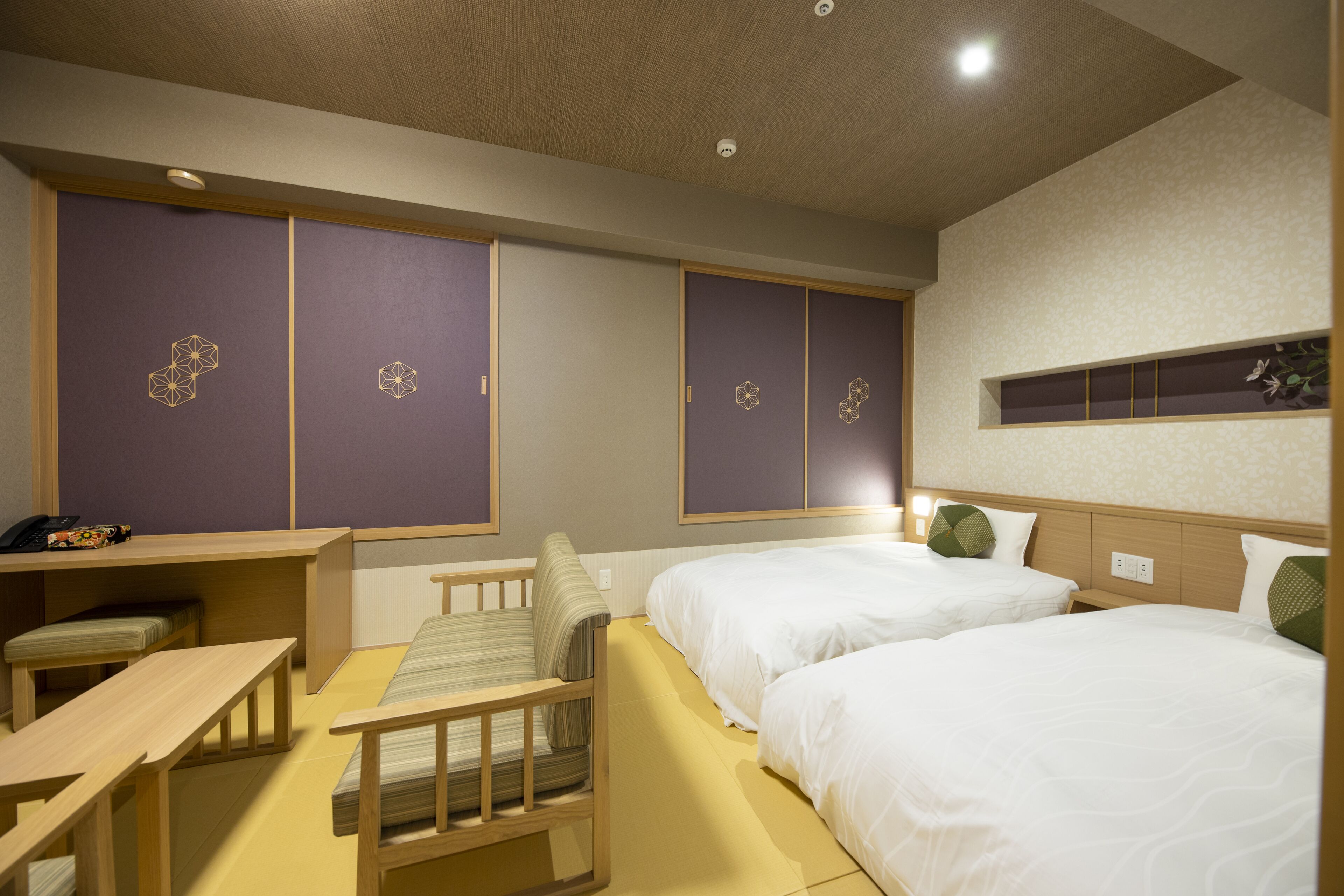 A hotel room with two beds, a desk, and a chair.