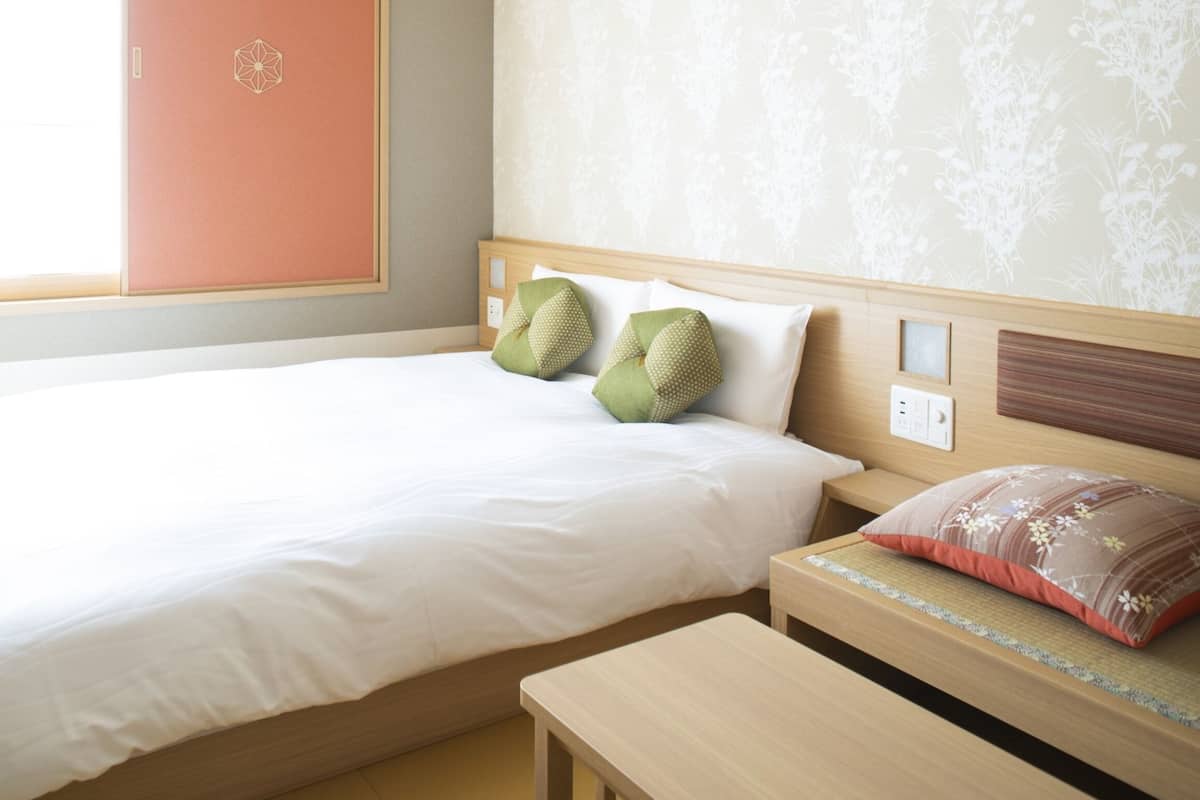 Une chambre d’hôtel avec un grand lit, deux oreillers, une table de chevet et une fenêtre donnant sur un beau paysage.