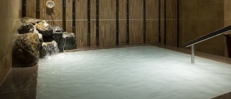 A hot spring area with a wooden wall, a clock, and a sign.