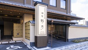 A building entrance with a sign indicating a Japanese-style hotel, a wheelchair-accessible ramp, and a staircase leading to the entrance.