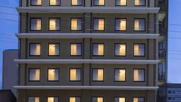 Um hotel com vários andares e design moderno, com entrada central e diversas janelas em cada piso.