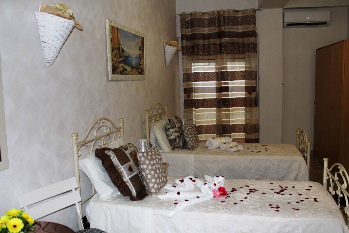 A bedroom with two single beds, a painting on the wall, and a shower curtain.