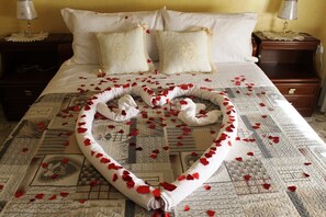 A bed with a heart-shaped arrangement of towels and rose petals. - B&B Sogni d'Oro (Reggio Calabria)