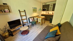 Ein modernes Wohnzimmer mit Sofa, Fernseher und Essbereich mit Stühlen und Tisch.