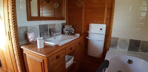 A bathroom with a wooden vanity, a white sink, a mirror, a towel rack, and a white toilet. - Roulotte La Grand Ourse (Anla)