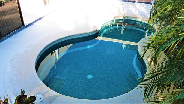 Una piscina rodona amb una superfície d'aigua blava cristal·lina, envoltada per un solàrium de formigó.