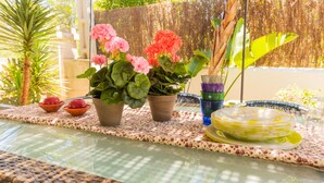 Une table avec des plantes en pot, un verre d’une boisson violette et une pile d’assiettes jaunes.