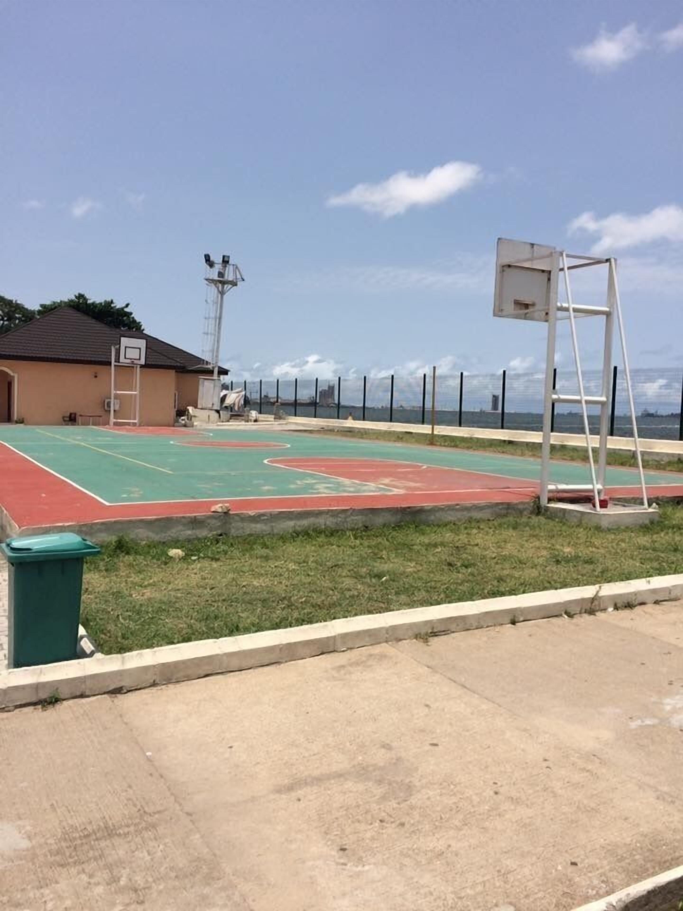 An outdoor basketball court with a building in the background.
