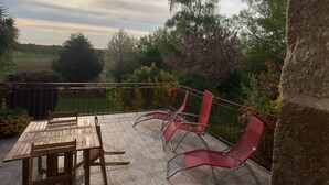 Eine Terrasse im Freien mit Tisch und Stühlen, umgeben von einem Geländer und Pflanzen.