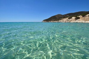 Una vista despejada del litoral, con aguas turquesas poco profundas y una playa de arena.