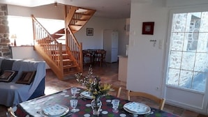 Un comedor con mantel de lunares, sillas de madera y una escalera que lleva a otra habitación.