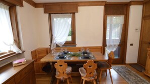 A dining area with a wooden table set for four, surrounded by wooden chairs. - Punta Nera Apartment: WI-FI and garden. (Cortina d´Ampezzo)