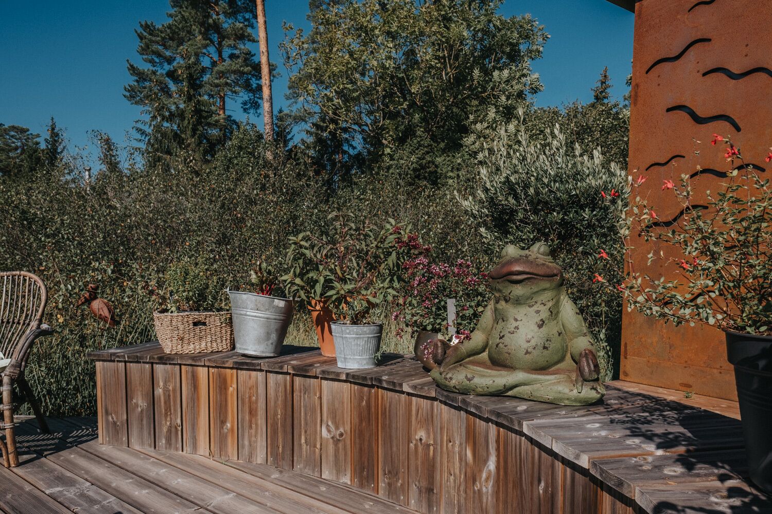 Un banco de madera con plantas en macetas y una estatua de rana.