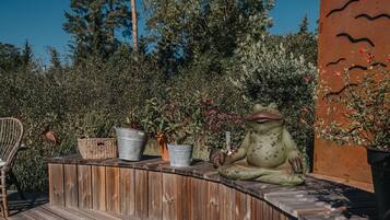 Un banco de madera con plantas en macetas y una estatua de rana.