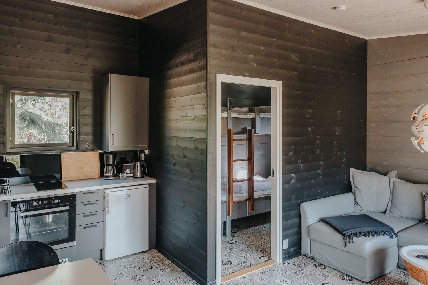 Una habitación compacta y moderna con kitchenette, un sofá y una escalera que lleva a una cama superpuesta.