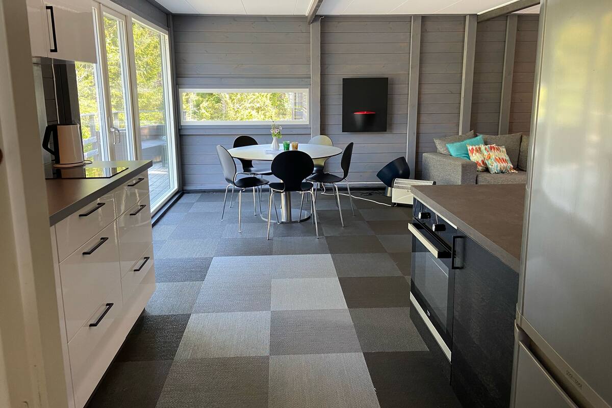 A modern kitchen with a dining area, large windows, and a built-in oven.