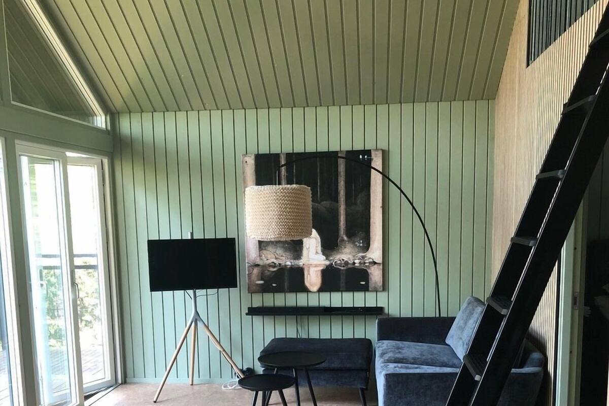 A room with a sofa, a small table, a chair, a TV, and a ladder.