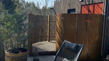 A wooden deck with a metal chair and a table, surrounded by a wooden fence and a potted plant.