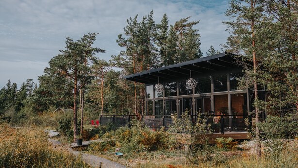 A modern cabin with large glass windows, surrounded by dense forest. - Mavens Kustnära Stugor (Lärbro)