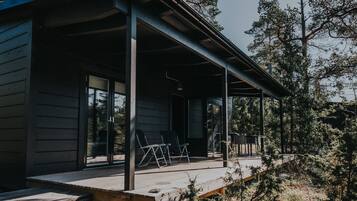 A wooden cabin with a covered porch, large windows, and a deck area.