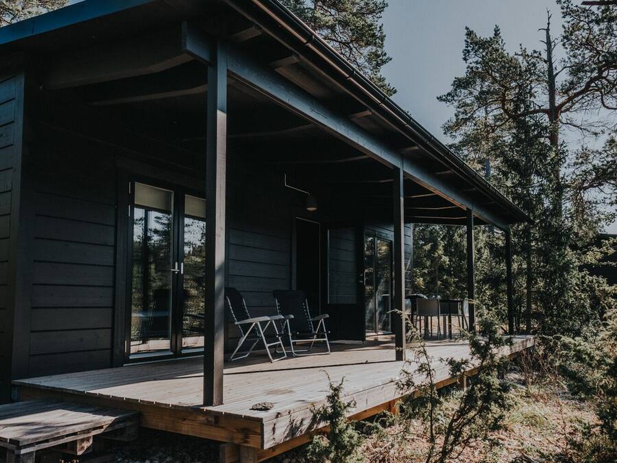 A wooden cabin with a covered porch, large windows, and a deck area.