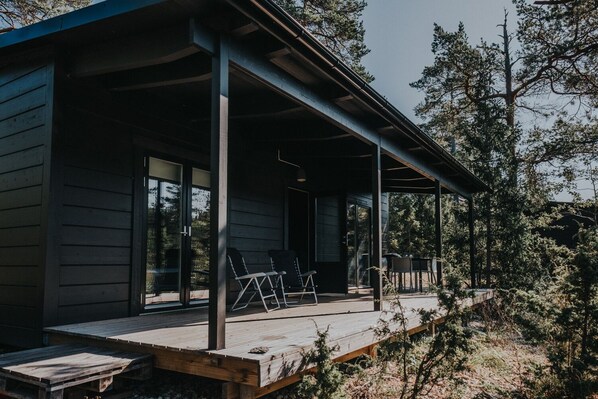 Una cabaña de madera con un porche cubierto, ventanas amplias y una terraza.