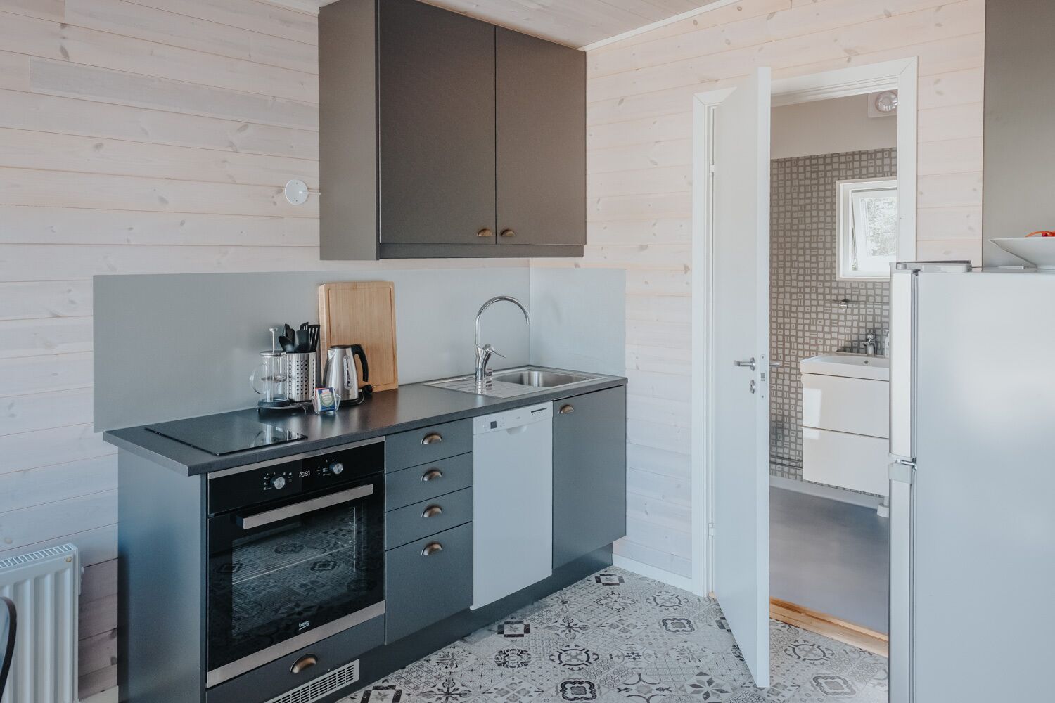 A compact kitchen with a built-in oven, a sink, and a dishwasher.