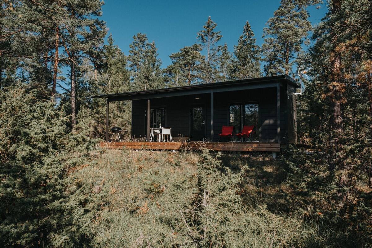 A cabin with a wooden deck, two red chairs, and a table.