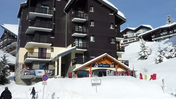 A multi-story hotel with balconies, ski equipment, and a ski lift in the background. - Cozy 2-room apartment, 5 people, Les Saisies (Les Saisies)
