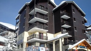A multi-story building with balconies, a ski resort sign, and snow-covered surroundings. - Cozy 2-room apartment, 5 people, Les Saisies (Les Saisies)