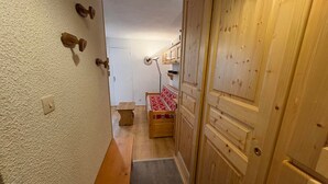 A narrow hallway with a wooden door, a small bench, and a bed with a patterned bedspread. - Cozy 2-room apartment, 5 people, Les Saisies (Les Saisies)