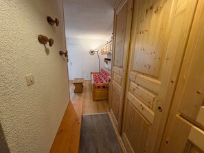 A narrow hallway with a wooden door, a small bench, and a bed with a patterned bedspread. - Cozy 2-room apartment, 5 people, Les Saisies (Les Saisies)