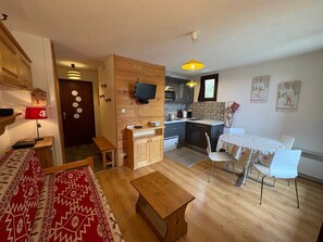 Un espacio habitable compacto con kitchenette, comedor y zona de estar con alfombra estampada.