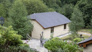 A small stone building with a sloped roof, surrounded by dense greenery. - Heather House (Glendalough)