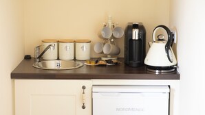 A kitchenette with a sink, a coffee maker, a kettle, and storage containers. - Heather House (Glendalough)