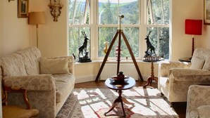 A cozy living room with a large window, a tripod, and a chessboard. - Heather House (Glendalough)